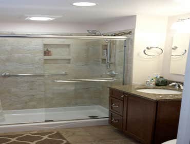 Farina - Bathroom This bathroom remodel included an acrylic pan with seat, 12 x 24 tile in a light cream and a decorative stone and glass border trim. 