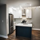 Leonardtown Kitchen Renovation An elegant white kitchen featuring a sleek black island with a white countertop as the centerpiece, complemented by cust