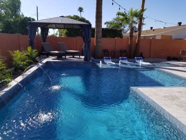 Custom Pools Wet edge pool in phoenix with sun shelf, splash pad and hardscape/landscape.