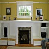 Shamburg Heating LLC Project Before and after a fireplace installation with mantle and cabinets.