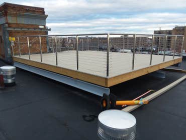 Roof top deck PVC decking with stainless steel cable railing on 7 story condo building. Includes extensive prep to locate bearing points in old buildin
