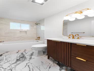 Tracy | Guest Bathroom This bathroom remodel features elegant marble-look tile on the walls and striking high-contrast porcelain flooring. We installed