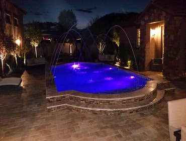 Custom Pools Wet edge pool in phoenix with sun shelf, splash pad and hardscape/landscape.