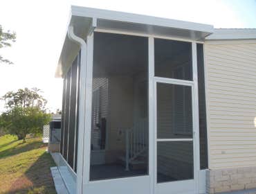 Screen Room and Slad Walkway White screen room with pan roof, gutters, and charcoal screen as well as slab leading to rear screen room and AC handler