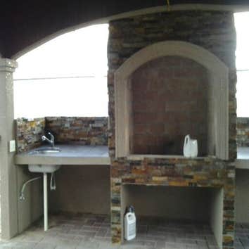 PROJECT FROM ARJONA REMODELING Outdoor palapa includes a chimney made of stone and stucco. The chimney also has a sink on one side and on the other the