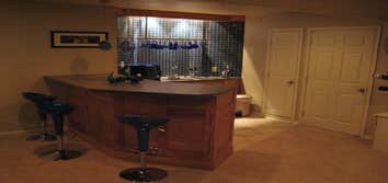 Finishing a Basement The client wanted three distinct areas in the basement - a home theater, a gym and a bar - along with a powder room. We extended 