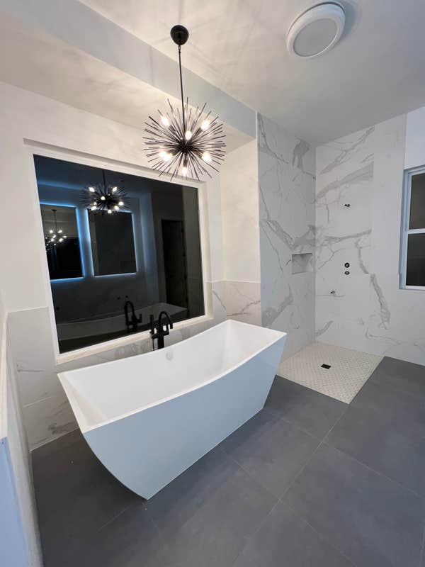 Primary bathroom. Tub, lighting, window, all tile.