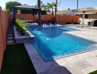Custom Pools Wet edge pool in phoenix with sun shelf, splash pad and hardscape/landscape.