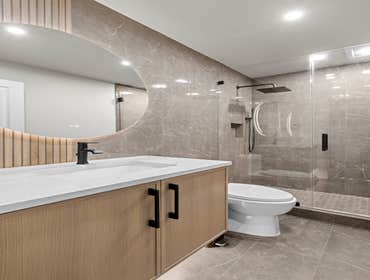 Jamaica Residence – Modern Stone Bathroom This waterfront bathroom was designed with a focus on texture, contrast, and clean visual alignment, reflecti