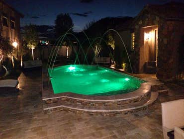 Custom Pools Wet edge pool in phoenix with sun shelf, splash pad and hardscape/landscape.