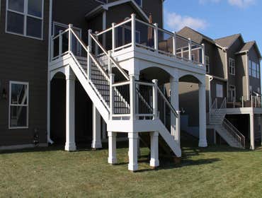 Custom Deck in Eden Prairie Trex decking in Spiced Rum with Trex railing (with glass panels and drink rail in Trex Lava Rock), Azek PVC post wraps and 