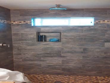 Eatonville Children's Bath Quality tile shower, very rich and stunning. Installed with 6in x 24in porcelain tiles in a darkened wood style. I would lik