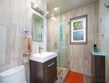 Bathroom-Woody Porcelain Plank Tile. Floor tiled inlaid around window and shampoo shelf. Pebble Rock Shower Floor.