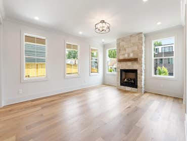 Open living room at 1135 Delmas Ave, East Nashville by CJMC Build: stone fireplace, wide plank floors, and abundant natural light.