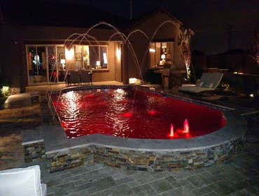 Custom Pools Wet edge pool in phoenix with sun shelf, splash pad and hardscape/landscape.
