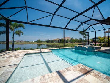 Pool Enclosure and Pavers Bronze pool cage with picture window and charcoal screen set over Euro slab pavers.