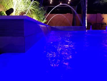 Custom Pools Wet edge pool in phoenix with sun shelf, splash pad and hardscape/landscape.