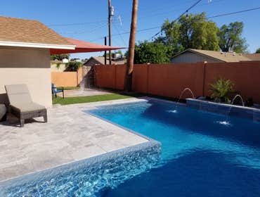 Custom Pools Wet edge pool in phoenix with sun shelf, splash pad and hardscape/landscape.