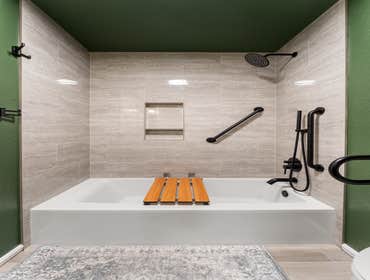James & Lisa | ADA Bathroom ADA bathroom remodel with accessibility in mind—featuring a tub with matte black grab bars, handheld shower, and a fold-dow