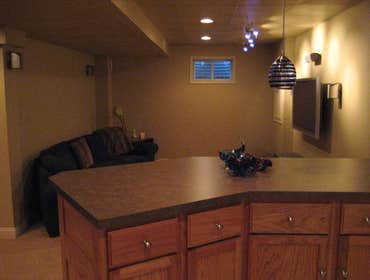 Finishing a Basement The client wanted three distinct areas in the basement - a home theater, a gym and a bar - along with a powder room. We extended 