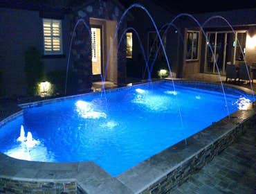 Custom Pools Wet edge pool in phoenix with sun shelf, splash pad and hardscape/landscape.