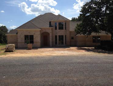 Photo(s) from Kelley Homes, Inc. Stone and brick exterior with arched entry and double bay windows. Grand entry with dramatic curved staircase to seco