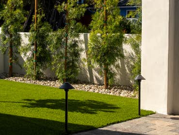 Front yard landscaping Enclosed yard with a retaining wall, and installed turf, pavers, and river rock garden border.
