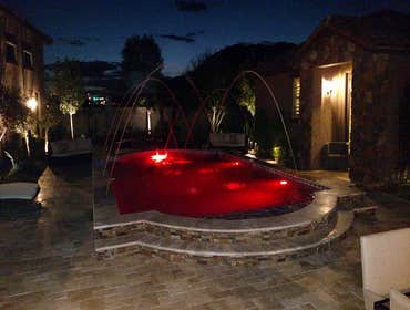 Custom Pools Wet edge pool in phoenix with sun shelf, splash pad and hardscape/landscape.