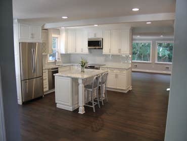 Kitchen Remodel Kitchen transformation including marble counter tops, custom white cabinets, dark stained natural hardwood flooring, glass tile back sp