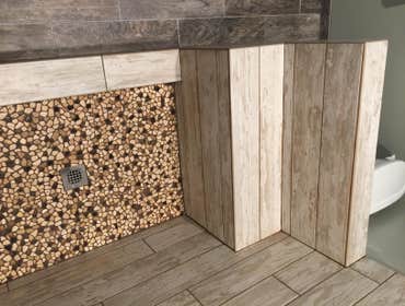 Shower remodel Wood plank porcelain tile with glass mosaic shampoo box, and stone floor. All bull nosing done by hand.