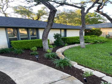 Side yard with stone border, hedges, and new windows