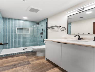 Katie | Guest Bathroom This guest bathroom remodel features a refreshing design with vertical aqua tiles and sleek black fixtures. We installed the wal