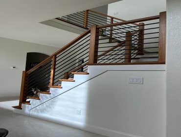 Stair railing New oak newel posts, powder coated black steel horizontal bars. Matching stain on exposed sides of steps.