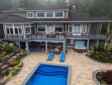 Mainili Project Custom Duvall, WA outdoor living space with Castle Gate decking, cable railing, undercover ceiling, heaters, and a Dekton Laurent kitch